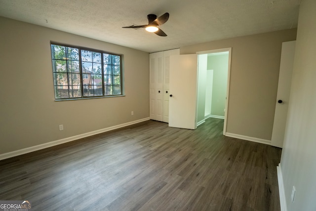 unfurnished bedroom with a closet, ceiling fan, a textured ceiling, and dark hardwood / wood-style flooring