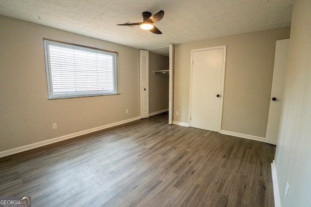 unfurnished bedroom featuring a closet, ceiling fan, a textured ceiling, and dark hardwood / wood-style flooring