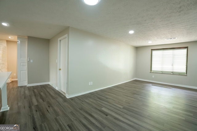 unfurnished living room with dark wood-type flooring and a textured ceiling