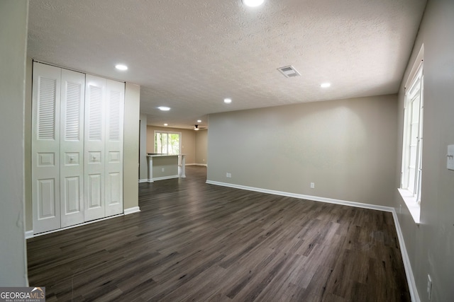 unfurnished living room with dark wood-type flooring and a textured ceiling