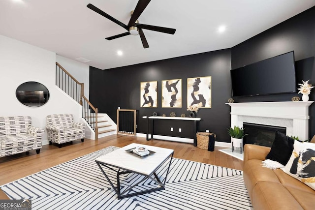 living room featuring ceiling fan, light wood-type flooring, and a high end fireplace