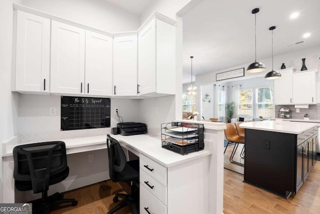 office with built in desk, light hardwood / wood-style floors, and a chandelier