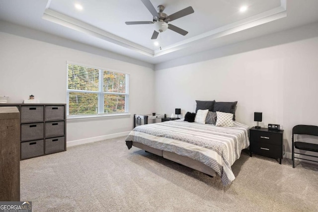 carpeted bedroom with ceiling fan and a raised ceiling