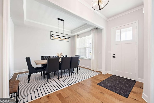 interior space with ornamental molding, a raised ceiling, and hardwood / wood-style floors