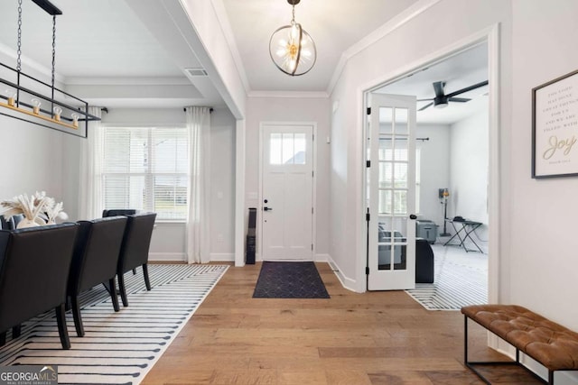 foyer with light hardwood / wood-style flooring, ceiling fan with notable chandelier, and crown molding