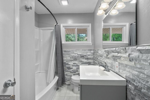 full bathroom with tile walls, vanity, shower / bath combo, toilet, and a notable chandelier