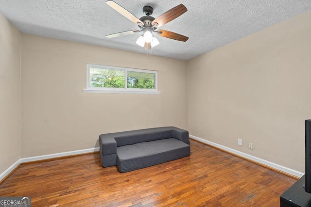 sitting room featuring ceiling fan, hardwood / wood-style floors, and a textured ceiling