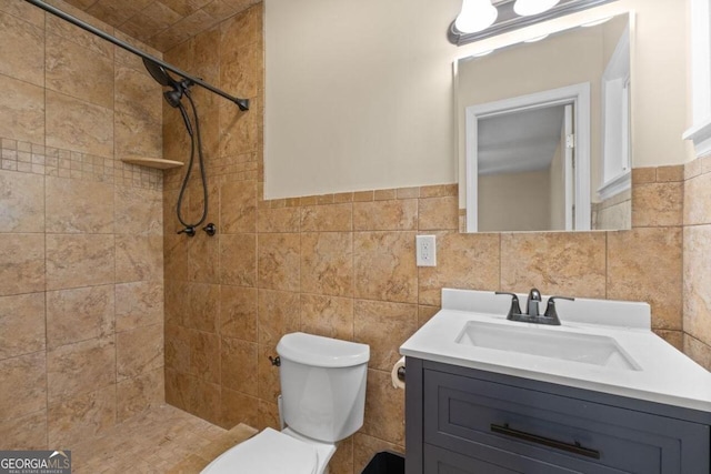 bathroom featuring tile walls, tiled shower, vanity, and toilet