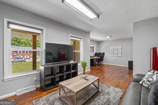 living room with a textured ceiling and dark hardwood / wood-style floors