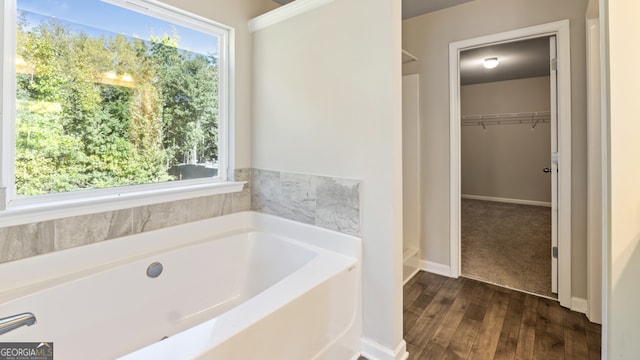 bathroom featuring wood-type flooring, a bathtub, and a wealth of natural light