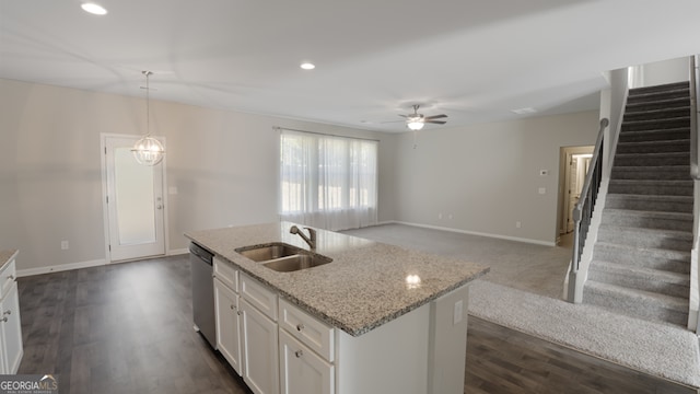 kitchen featuring pendant lighting, an island with sink, sink, white cabinetry, and light stone countertops