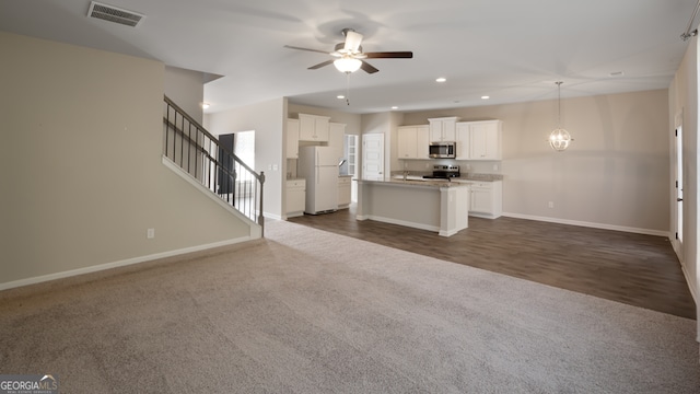 unfurnished living room with ceiling fan with notable chandelier and dark hardwood / wood-style floors