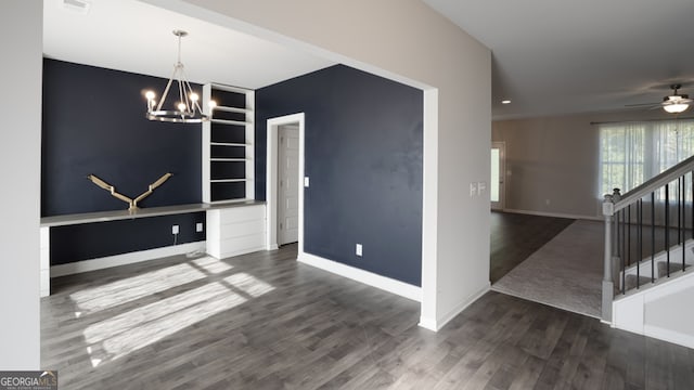 unfurnished dining area with ceiling fan with notable chandelier and dark hardwood / wood-style flooring