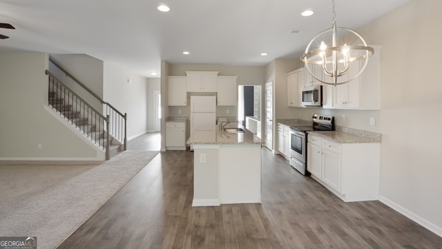 kitchen with light stone counters, white cabinets, decorative light fixtures, appliances with stainless steel finishes, and hardwood / wood-style floors