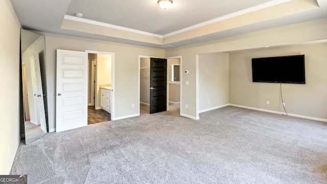 unfurnished bedroom featuring crown molding, a tray ceiling, connected bathroom, and carpet