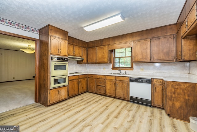 kitchen with light hardwood / wood-style floors, a textured ceiling, sink, backsplash, and white appliances