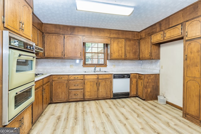 kitchen with light wood-type flooring, decorative backsplash, white appliances, and sink