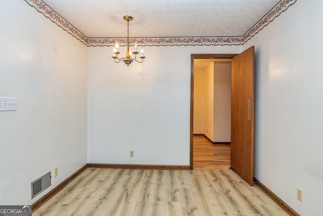 empty room with an inviting chandelier and light wood-type flooring