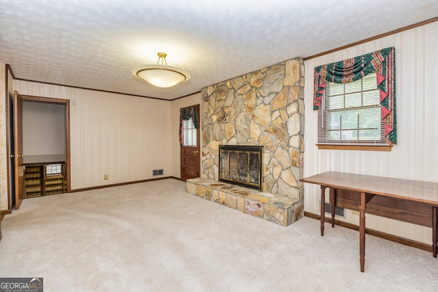 unfurnished living room with ornamental molding, a textured ceiling, a fireplace, and carpet flooring