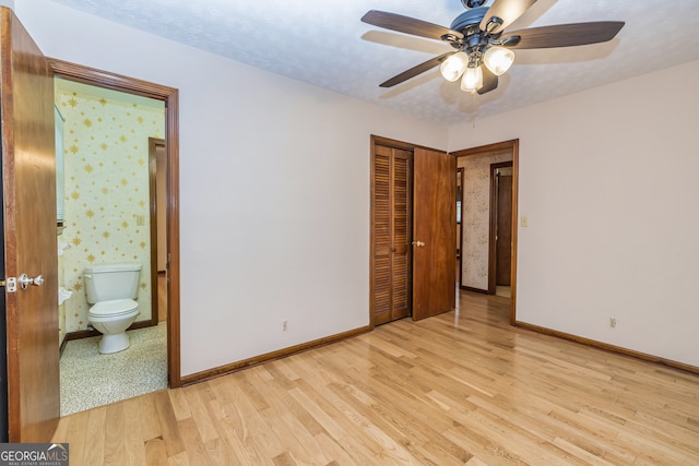 unfurnished bedroom with light wood-type flooring, connected bathroom, ceiling fan, and a closet