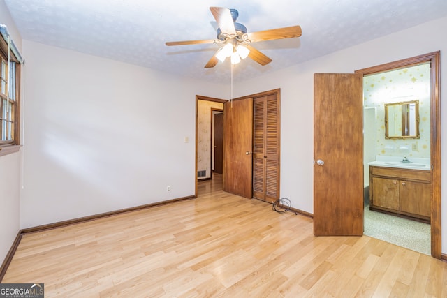 unfurnished bedroom with connected bathroom, a closet, ceiling fan, light hardwood / wood-style flooring, and sink