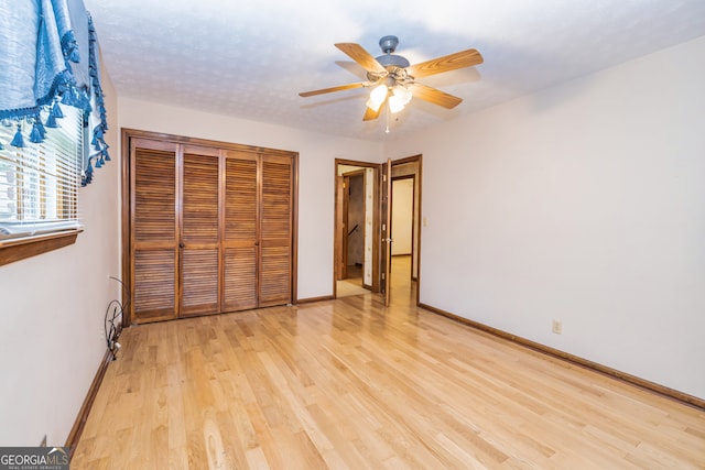 unfurnished bedroom with ceiling fan, a closet, and light hardwood / wood-style floors