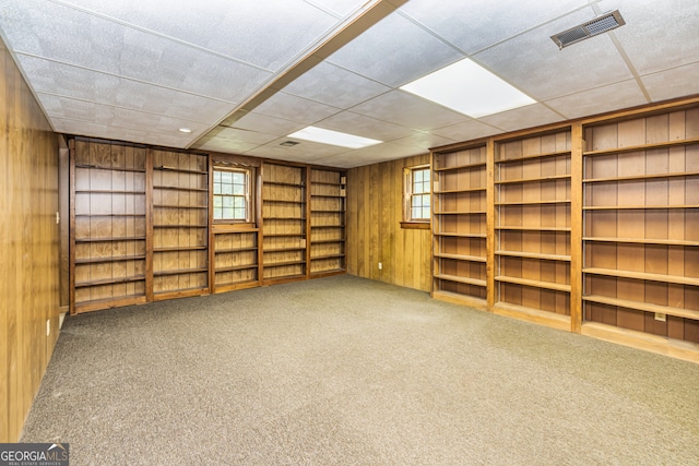 interior space featuring a drop ceiling and wood walls