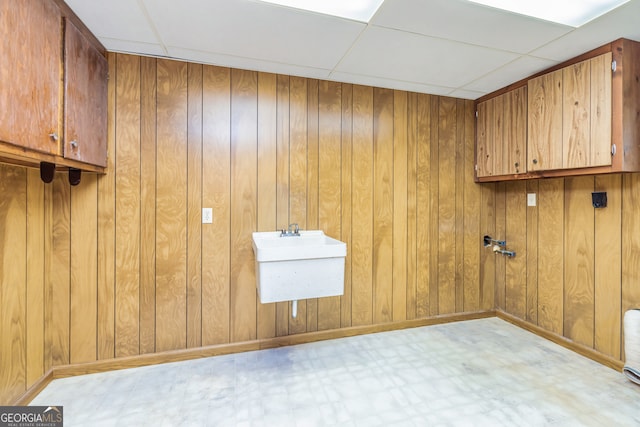 laundry area with cabinets, wooden walls, and sink