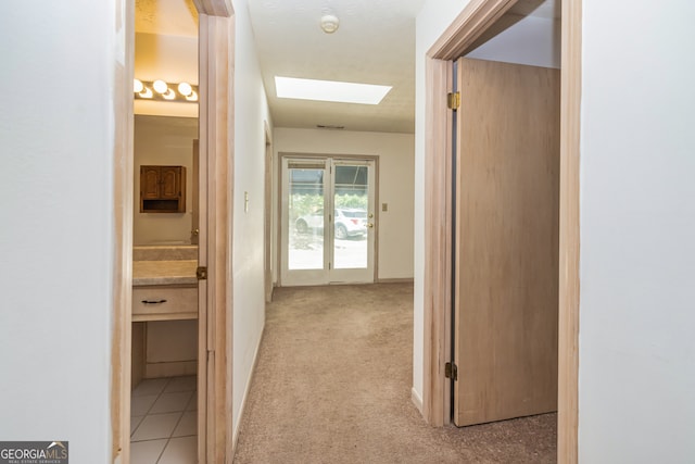 corridor with light carpet and a skylight