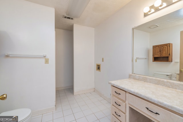 bathroom featuring vanity, tile patterned flooring, toilet, and a textured ceiling