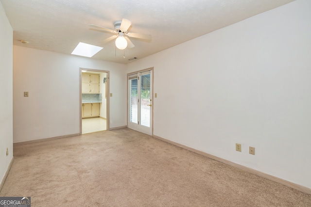 carpeted spare room featuring ceiling fan and a skylight