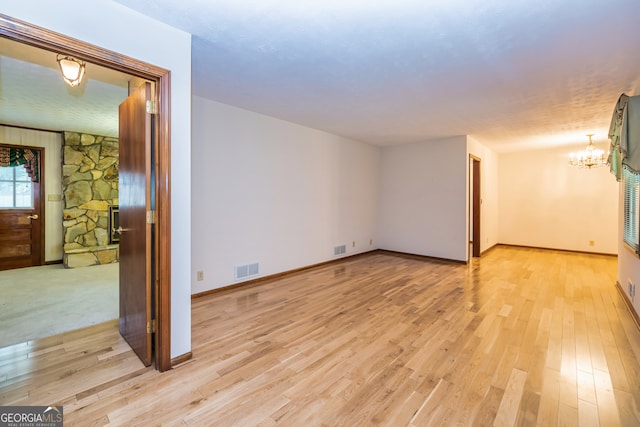 spare room with light hardwood / wood-style flooring and a notable chandelier