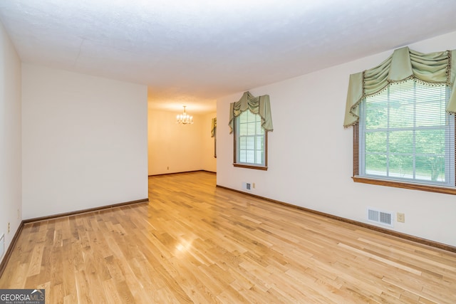 empty room featuring light hardwood / wood-style flooring and a chandelier