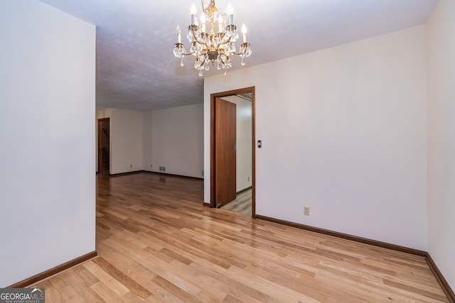 unfurnished room featuring a chandelier and light hardwood / wood-style floors