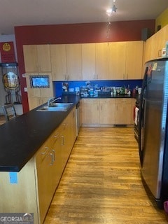 kitchen featuring light brown cabinets, light hardwood / wood-style floors, stainless steel fridge, and sink