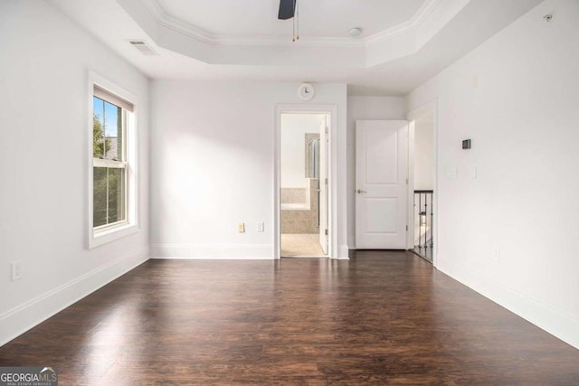 empty room featuring a tray ceiling, ceiling fan, dark wood-type flooring, and crown molding