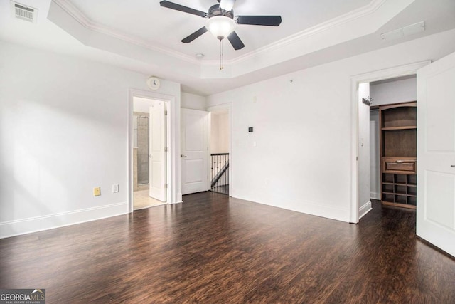 unfurnished bedroom with ceiling fan, a raised ceiling, crown molding, and dark hardwood / wood-style flooring