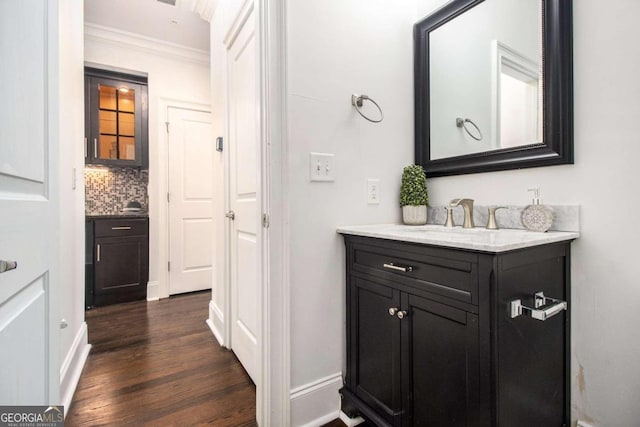 bathroom featuring vanity, hardwood / wood-style flooring, crown molding, and tasteful backsplash