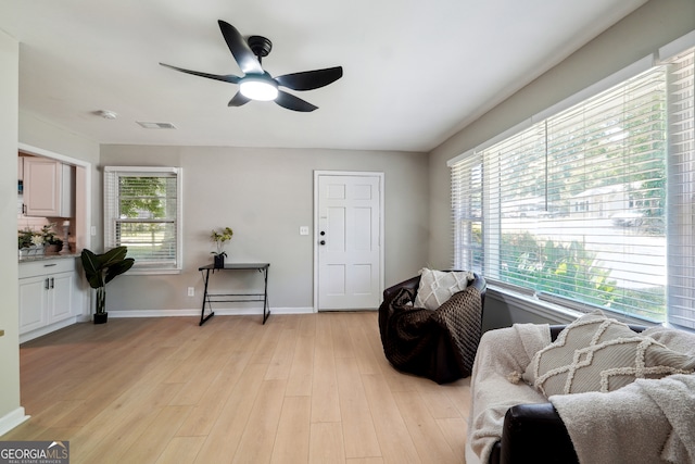 living area with light wood-type flooring, a healthy amount of sunlight, and ceiling fan