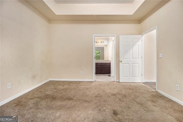 carpeted spare room featuring a raised ceiling