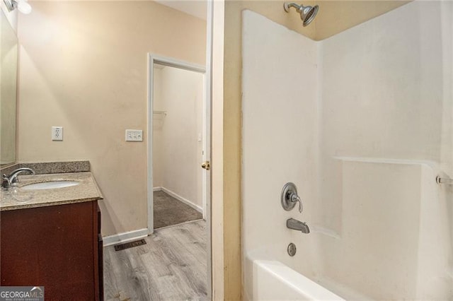 bathroom with hardwood / wood-style flooring, vanity, and shower / washtub combination