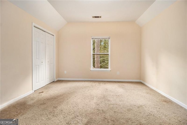 unfurnished bedroom with carpet flooring and lofted ceiling