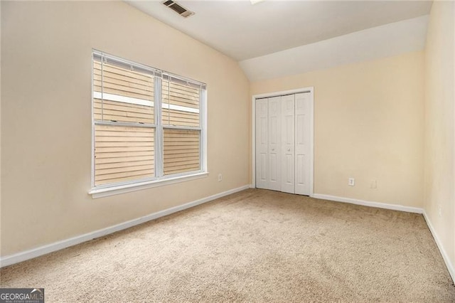 unfurnished bedroom with a closet, lofted ceiling, and carpet flooring