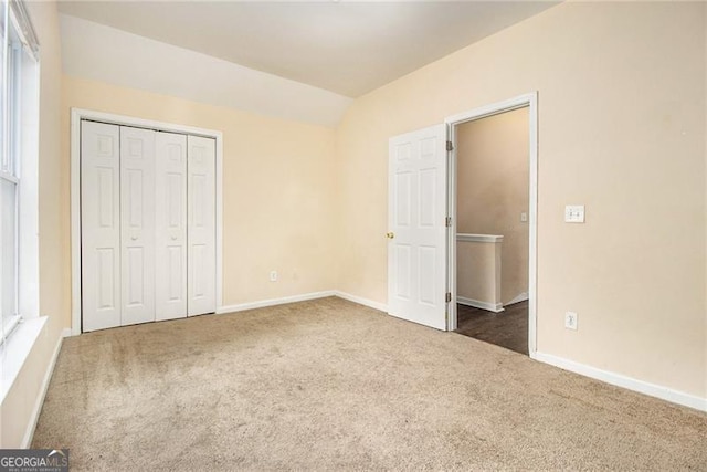 unfurnished bedroom featuring a closet, lofted ceiling, and dark colored carpet