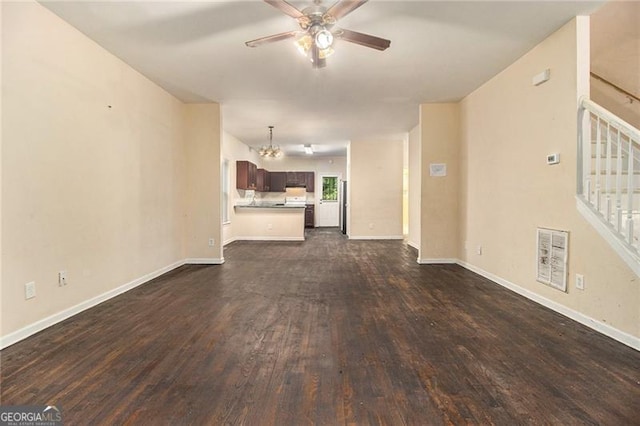 unfurnished living room with ceiling fan with notable chandelier and dark hardwood / wood-style floors