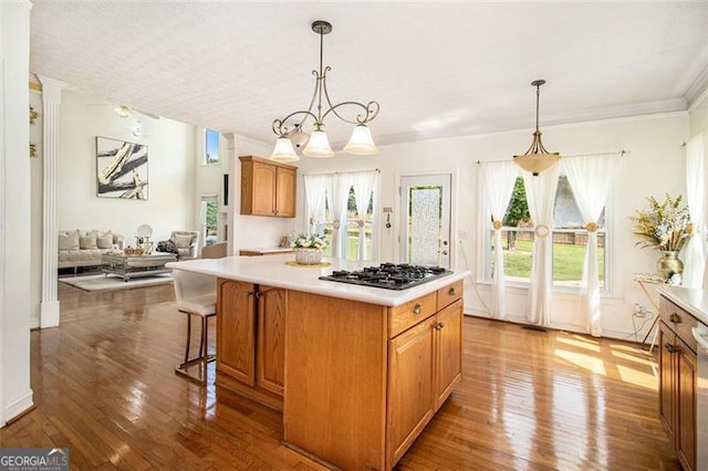 kitchen with a kitchen island, light countertops, decorative light fixtures, and black gas stovetop