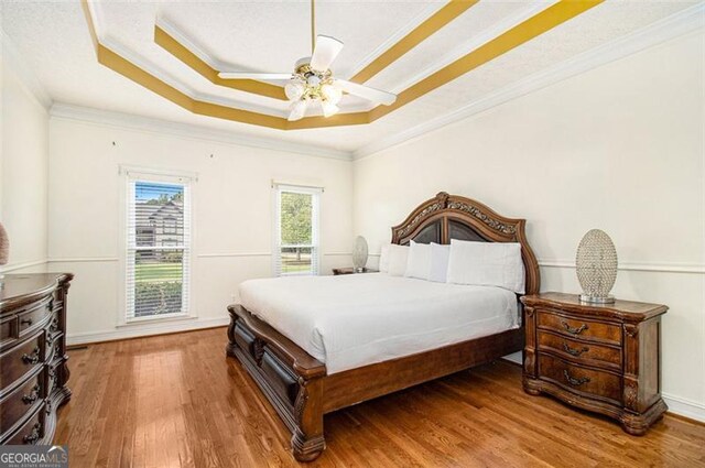 bathroom with hardwood / wood-style floors, tiled tub, vanity, and crown molding