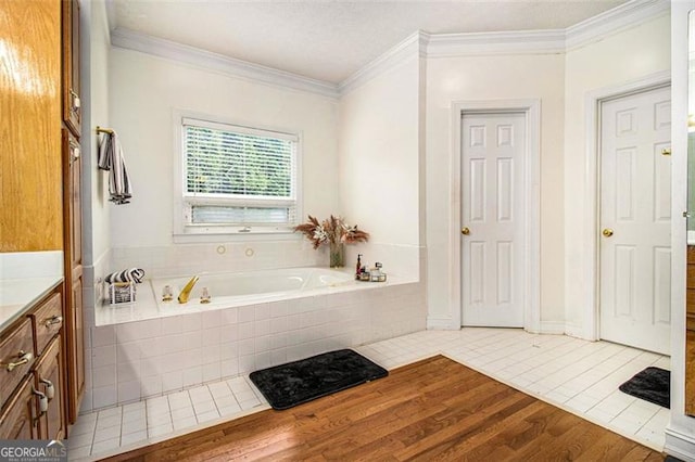 full bathroom featuring a garden tub, crown molding, vanity, and wood finished floors