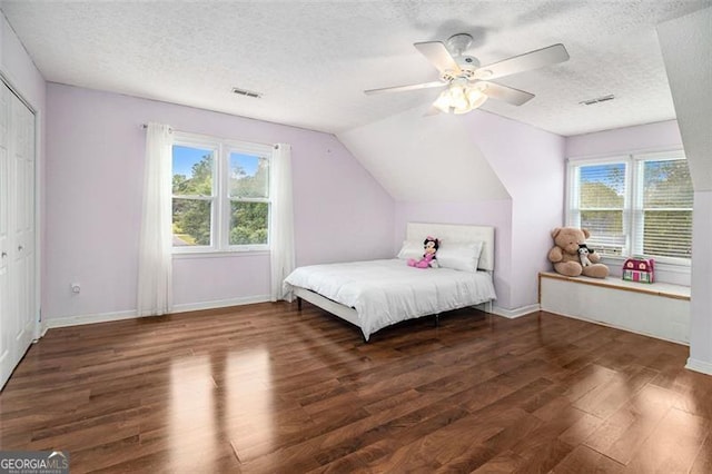 bedroom with dark wood-style floors, multiple windows, visible vents, and vaulted ceiling