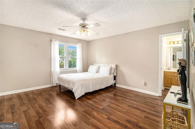 bedroom with a textured ceiling, connected bathroom, dark wood-type flooring, and ceiling fan